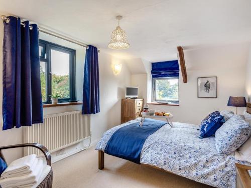 a bedroom with a bed with blue sheets and windows at 3 Bed in Lifton oc-tcoah in Broadwoodwidger