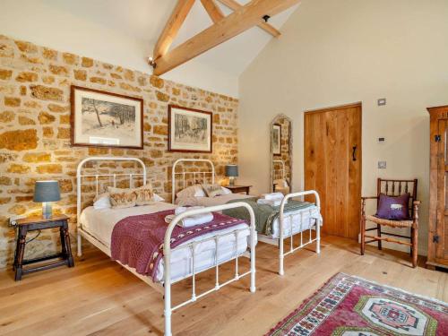 two beds in a room with a stone wall at 2 Bed in Stoke Abbott oc-94406 in Stoke Abbott