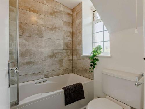 a bathroom with a tub and a toilet and a window at 2 Bed in Bideford oc-60430 in Westward Ho