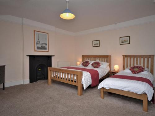 two beds in a room with a fireplace at 3 Bed in Exeter oc-harri in Talaton