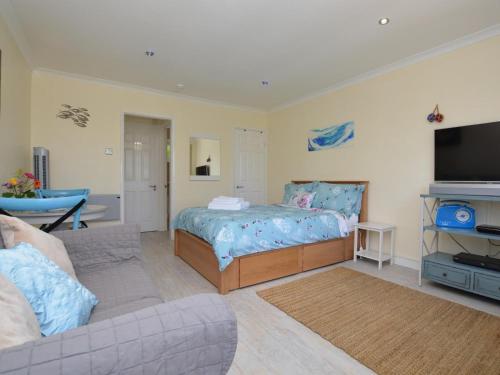 a bedroom with a bed and a couch and a tv at 1 Bed in Bridport oc-41890 in Charmouth
