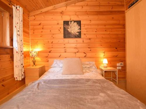 a bedroom with a bed in a wooden cabin at 2 Bed in Tiverton oc-wonha in Bampton