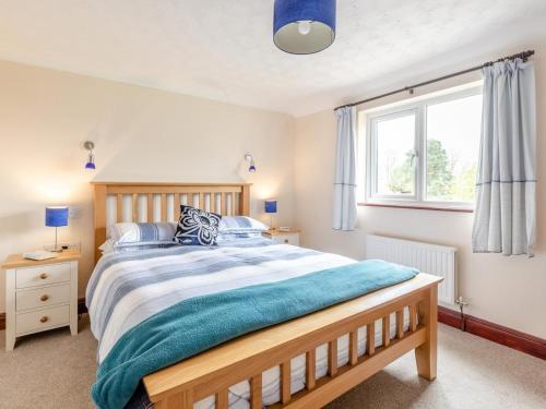 a bedroom with a wooden bed with a blue blanket at 2 Bed in Taunton oc-41906 in Cothelstone