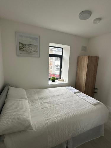 a white bedroom with a bed and a window at Milk Market Inn in Limerick