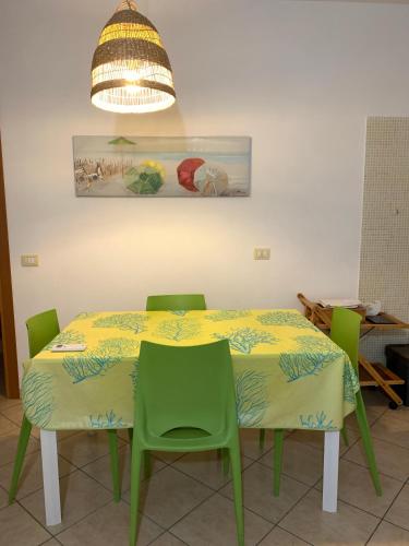 a dining room table with two green chairs and a light at Arbaría vacation home in Cava D'aliga
