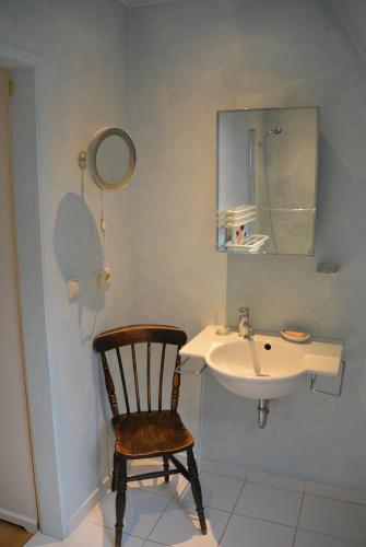a bathroom with a chair and a sink at Doppelzimmer am Park in Bremerhaven