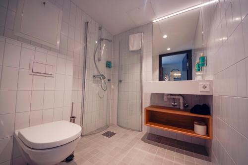 a white bathroom with a toilet and a shower at Klingenberg Hotel - Årdal in Årdalstangen