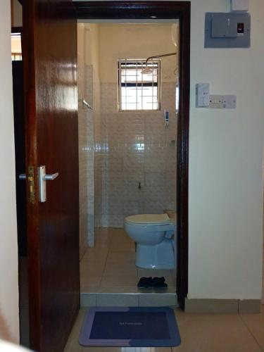 a bathroom with a toilet and a glass door at Rose homes in Mombasa