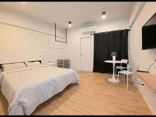 a bedroom with a white bed and a table at My Space 77 in Ban Khlong Khwang Klang