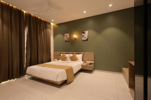 a bedroom with a large bed and a green wall at Hotel Pune Pride, Baner in Pune