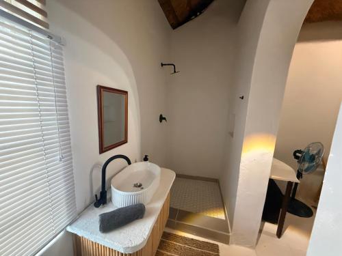 ein weißes Badezimmer mit Waschbecken und Spiegel in der Unterkunft Lemon Cottage in Bela-Bela