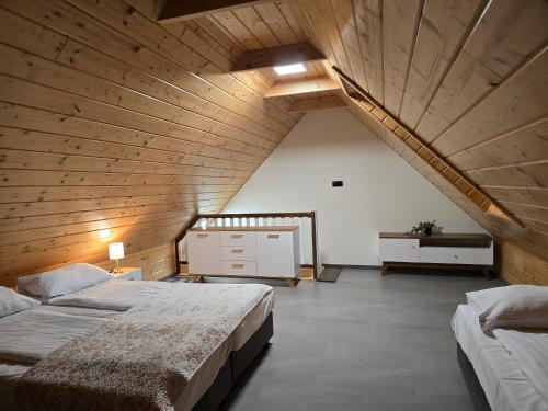 two beds in a room with a wooden ceiling at Dolina Biebrzy - Chata Flisaka in Wroceń