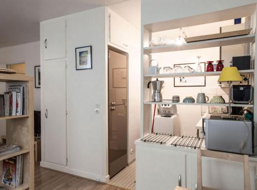 a kitchen with white cabinets and a door leading into a room at Le Studio 1517 in Le Kremlin-Bicêtre