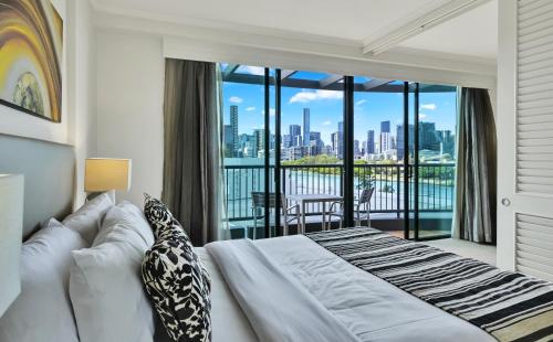 a bedroom with a bed and a view of the city at Cosmo Apartment Hotel in Brisbane
