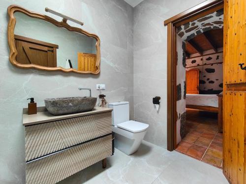 a bathroom with a sink and a toilet and a mirror at Casa Morro Herreno in Las Breñas