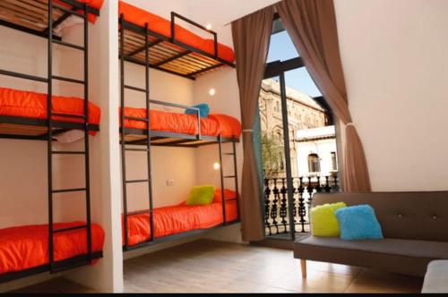 a room with bunk beds with a couch and a window at Real Ros Hostel in Rosario