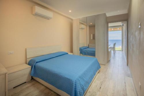 a bedroom with a blue bed and a view of the ocean at Casetta sulla Spiaggia - HelloElba in Capoliveri