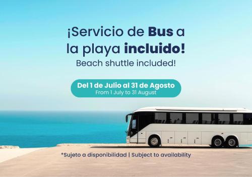 a white bus parked on a beach with the ocean at Port Denia in Denia