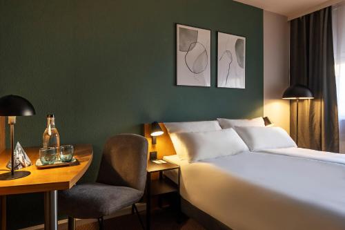 a hotel room with a bed and a desk and a chair at ACHAT Hotel Braunschweig in Braunschweig