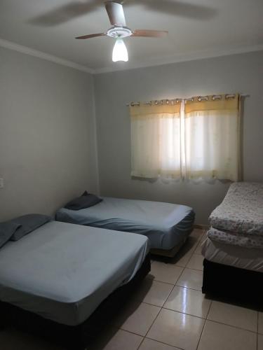 a bedroom with two beds and a ceiling fan at Paz e tranquilidade in Indaiatuba