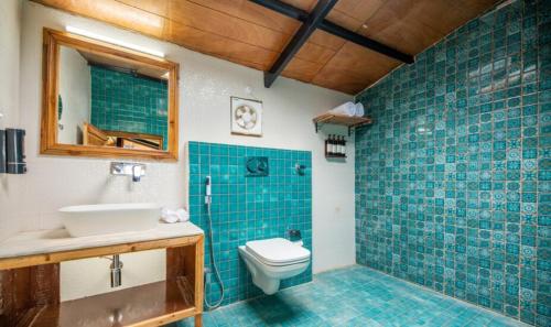 a bathroom with a toilet and a sink and blue tiles at THE CEDAR CASTLE in Mukteshwar