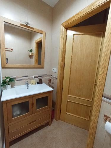 a bathroom with a sink and a mirror and a door at El DESAFÍO in Riópar