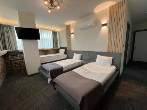 a hotel room with three beds and a flat screen tv at Hotel ABBARA in İzmir