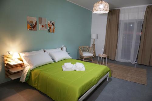 a bedroom with a green bed with two towels on it at Farina Apartments in San Nicola La Strada