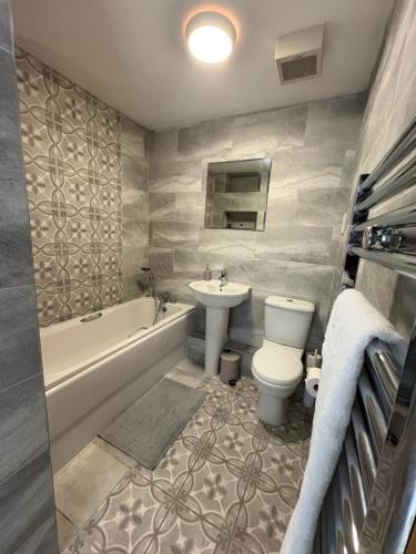 a bathroom with a sink and a toilet and a bath tub at Salt House, Stunning Swansea Marina Townhouse Sleeps 12, Beach & Arena in Swansea