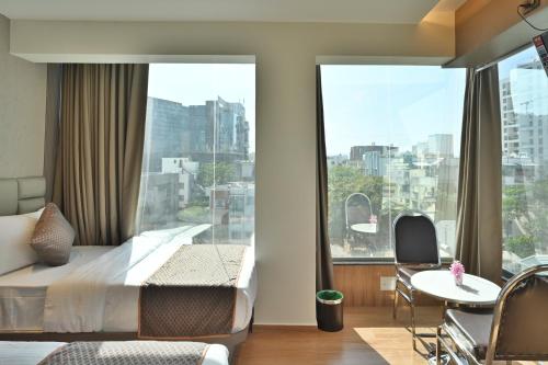 a bedroom with a bed and a large window at Hotel Emersion Residency in Pune