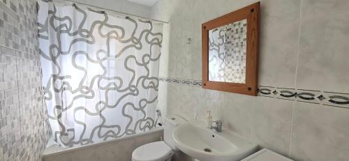 a bathroom with a sink and a toilet and a mirror at Peñoncillo Beach in Torrox Costa