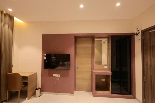 a hotel room with a desk and a tv on the wall at Hotel Pune Pride, Baner in Pune