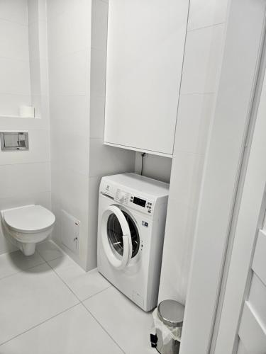 a white bathroom with a washing machine and a toilet at Apartament Dobra Nocka 2 in Przeworsk