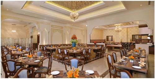 a restaurant with tables and chairs in a room at Indana Palace Jaipur in Jaipur