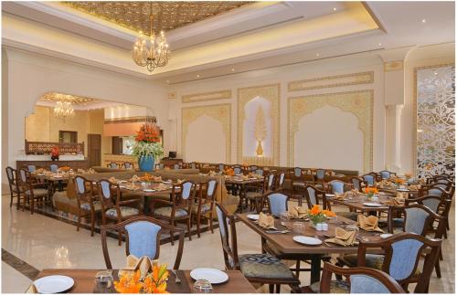 a dining room with tables and chairs and a chandelier at Indana Palace Jaipur in Jaipur