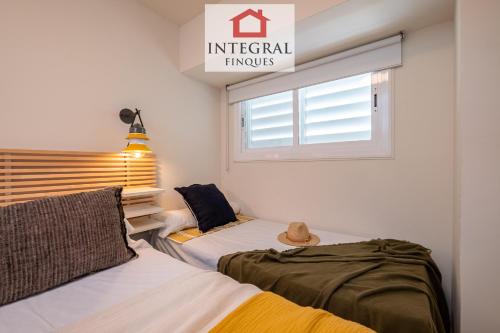 two beds in a room with a window at Horitzó Marí Palamós in Palamós