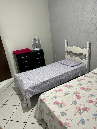 a bedroom with two beds and a dresser at Casa nova 2 quartos in Montes Claros