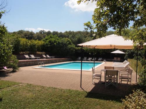 a pool with a table and chairs and an umbrella at Castello di Montalto in Castelnuovo Berardenga