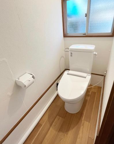 a white toilet in a bathroom with a window at 赤磐ベース in Akaiwa