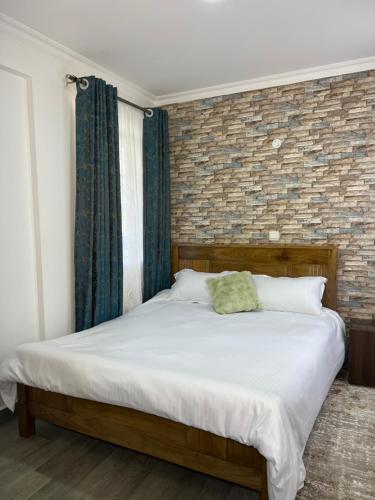 a bed in a bedroom with a brick wall at Kwetuhaven in Kiambu