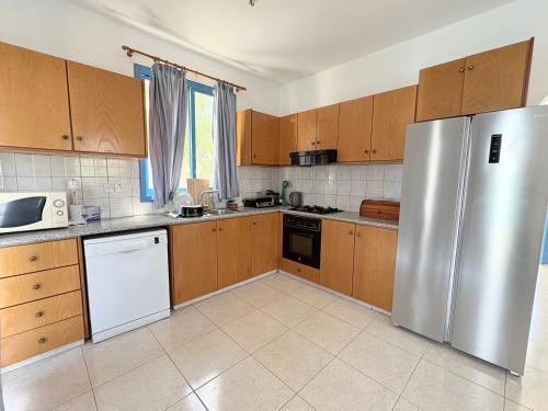 a kitchen with wooden cabinets and a stainless steel refrigerator at QUEEN EVRIDIKI & VILLA PANORAMA in Peyia