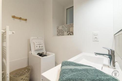 a bathroom with a sink and a washing machine at Gîte G1304 in Sottevast