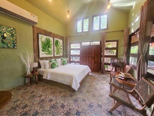 a bedroom with a bed in a room with windows at Three Hen Lakeside in Ban Na Nai