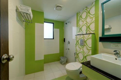 a green and white bathroom with a toilet and a sink at Cloud Dale Resort Munnar in Munnar