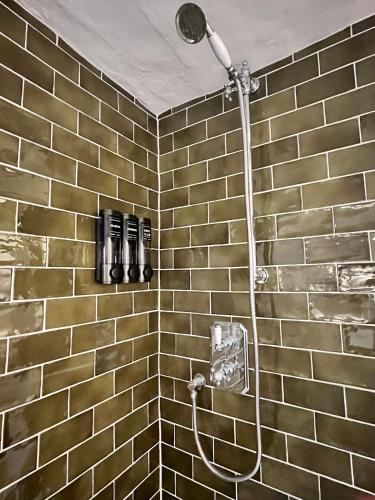 a shower in a bathroom with a brick wall at Habberley Hall Flat in Shrewsbury