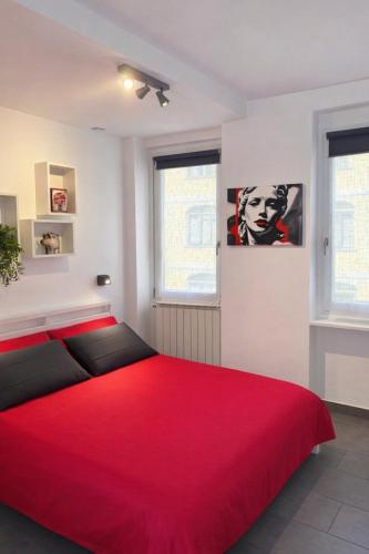 a red bed in a white room with a red blanket at Suite Casina al Lago in Lavena Ponte Tresa