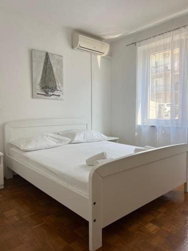 a white bedroom with a large white bed with a window at Villa Mare in Makarska