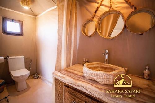 a bathroom with a wooden sink and mirrors at Sahara Safari Luxury Camp & Activities in Merzouga