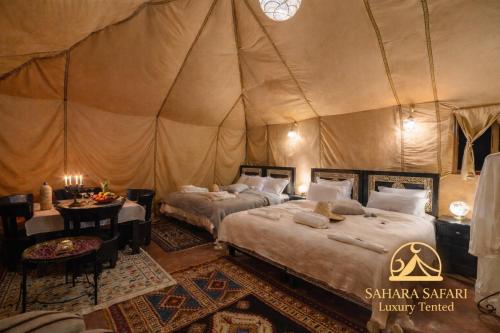 a bedroom with two beds in a tent at Sahara Safari Luxury Camp & Activities in Merzouga