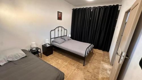 a bedroom with two beds and black curtains at Maison T2 avec terrasse et cours de 50m2 in Sorgues